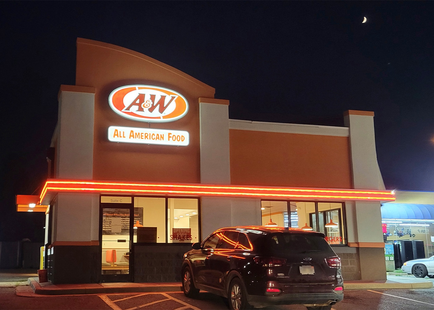 Exterior photo of an A&amp;amp;W Restaurant convenience store location at nighttime. A van is parked at the front of the building.