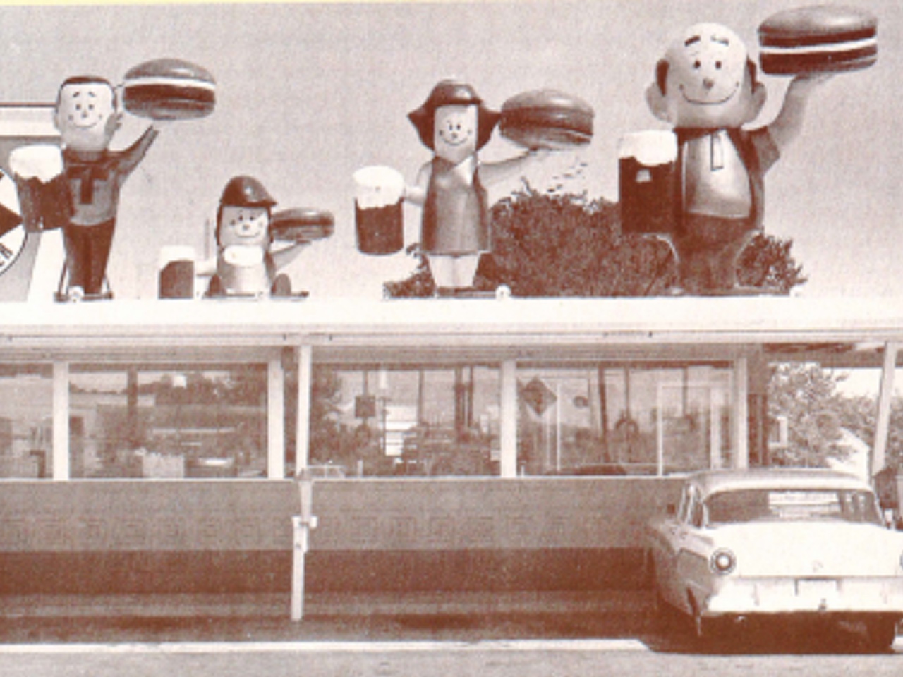 Vintage black and white photo of A&W Burger Family statues on top on A&W Restaurant